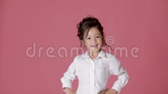 可爱的小女孩穿着白色衬衫在粉红色的背景上表现出不同的情绪视频的预览图