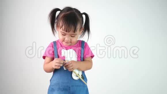 可爱的可爱的亚洲小女孩拿着画笔在白色背景上画的肖像视频的预览图