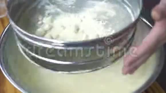 厨师将面粉过筛用于烤熟男性手在面包房的碗中通过筛子将面粉倒入碗中视频的预览图
