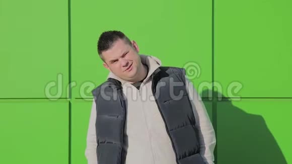 胖子在商店附近的绿色墙上摆姿势视频的预览图