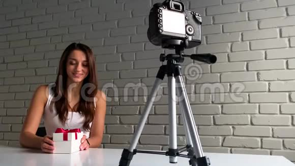 圣诞礼物一位留着长发的年轻女子坐在办公桌前在录制新博客的视频时与镜头交谈视频的预览图