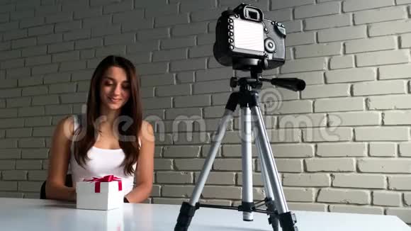 圣诞礼物一位留着长发的年轻女子坐在办公桌前在录制新博客的视频时与镜头交谈视频的预览图