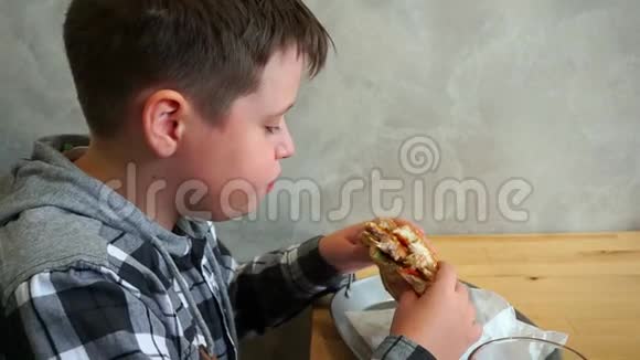 一个在咖啡馆里吃汉堡包的少年他饿得很慢视频的预览图