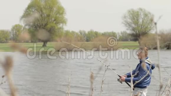 年轻人在大自然的背景下向河里扔鱼竿视频的预览图