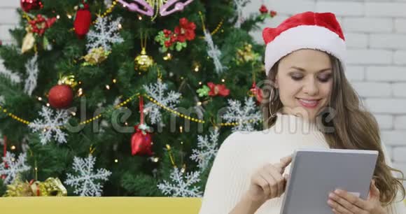 高加索女人在沙发上用平板电脑视频的预览图