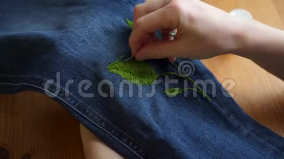 用缝纫针在牛仔裤上手工制作彩色刺绣图案视频的预览图