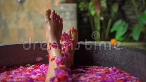 一位美丽的年轻女子在热带水疗中心洗花浴的慢镜头视频的预览图