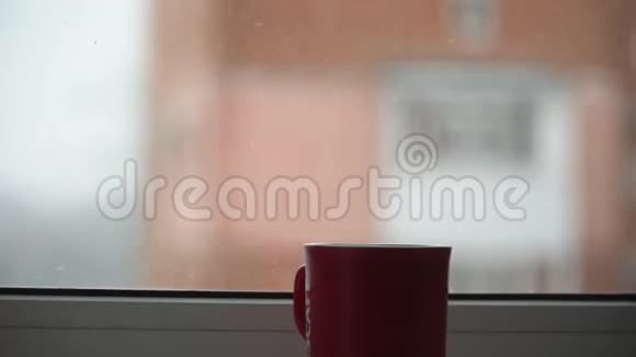 在白雪皑皑的冬天早晨舒适的印第安人在冬天的第四天站在窗户上蒸热茶视频的预览图