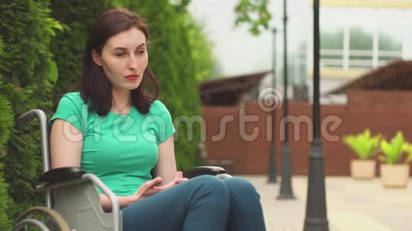坐在轮椅上的迷人的残疾悲伤女孩肖像概念视频的预览图