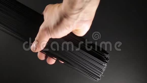 男人把墨鱼油墨意面条放在黑色背景上关闭视频视频的预览图