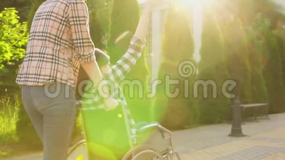 女孩在轮椅上与女朋友散步时残疾他们玩得很开心刺眼的阳光慢节奏视频的预览图