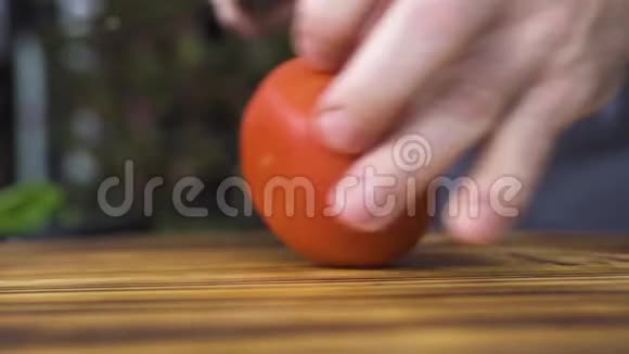 厨师把新鲜番茄切成两半放在木板上厨房用刀切番茄的男性手视频的预览图