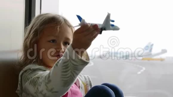 可爱的女孩在机场候机楼玩玩具飞机视频的预览图
