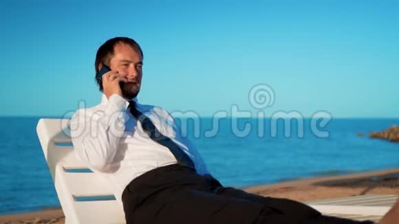 年轻的商人正在海滩上工作男专业人士坐在舒适的休息室里视频的预览图