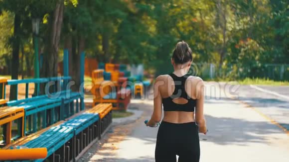 在公园的运动场上年轻运动员女子在舒适的运动场上跳着跳跃的斜坡后景视频的预览图