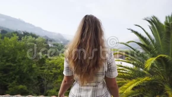村中山丘之间别墅阳台上的年轻女士视频的预览图