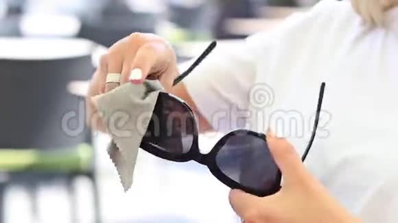 戴灰巾清洁太阳镜的女人视频的预览图