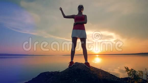 一个女人在湖边伸展一个女孩在日落的背景下在外面锻炼视频的预览图