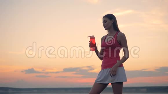 一个女人从一个红色的塑料瓶里喝关上视频的预览图