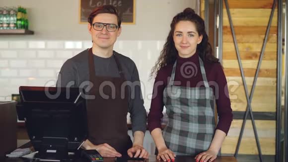 两个年轻漂亮的服务员站在咖啡屋的收银台微笑的画像成功的业务视频的预览图
