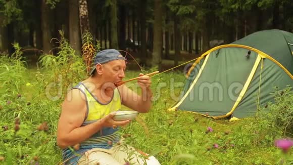 树林里帐篷附近的那个人正在吃早餐视频的预览图