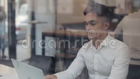 一个疲惫的年轻商人坐在咖啡馆的一张桌子旁用笔记本电脑工作自由职业者沟通IT疲惫视频的预览图