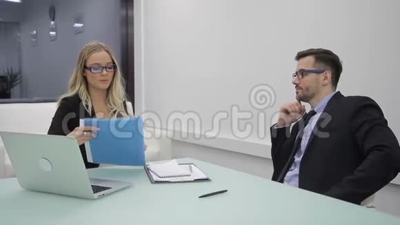 在办公室里一个女人和一个男人正在笔记本电脑附近学习文件视频的预览图