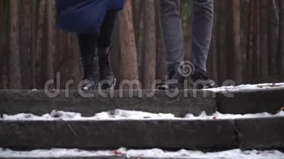在冬季公园里一对年轻夫妇从楼梯上跑下来一对夫妇脚夹起来视频的预览图