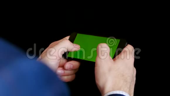 带砖计划的男人手里拿着黑色背景的智能手机手指触摸绿色的黑色触摸视频的预览图