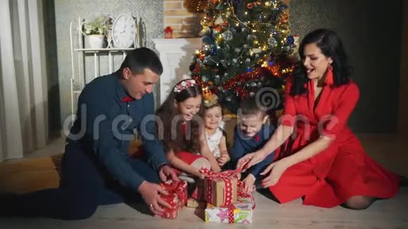 欢乐的五口之家正在开圣诞礼物新年之夜在圣诞树脚下视频的预览图