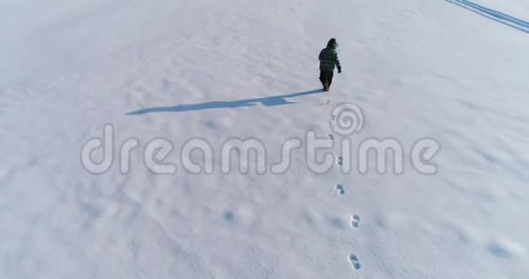 男孩正在一个覆盖着雪的地区奔跑躺在雪地上制作雪天使空中镜头视频的预览图