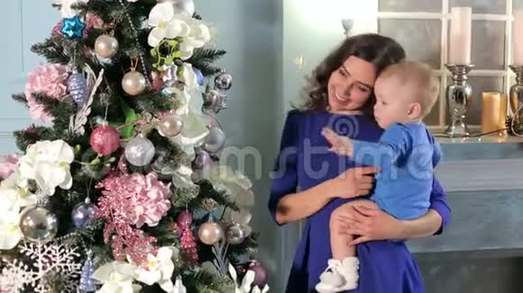 一位年轻的母亲带着一个新生的儿子在家里装饰圣诞树视频的预览图