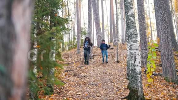 一个年轻的卷发女人和一个在斯堪的纳维亚散步的男孩在森林里一路下坡视频的预览图