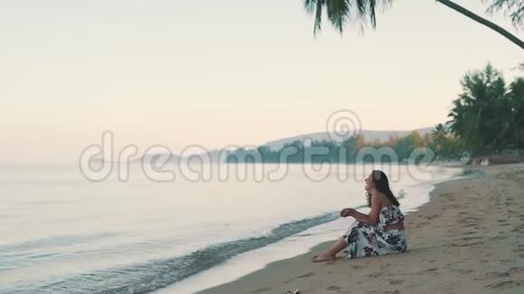 快乐的女孩坐在海边的沙滩上视频的预览图