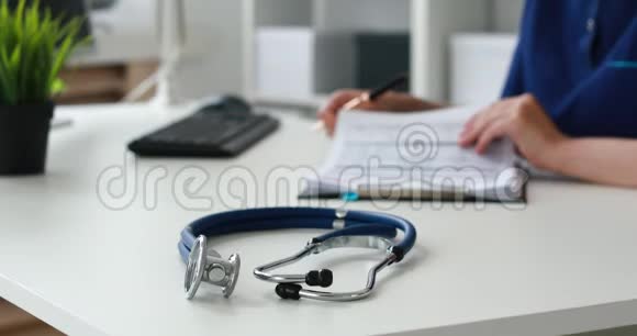 蓝色听诊器在桌子上的焦点在前台后面的医生填写文件视频的预览图