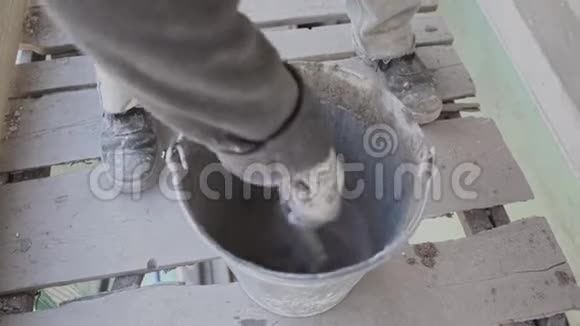 工人手在桶里用油漆刷搅拌湿的混凝土视频的预览图