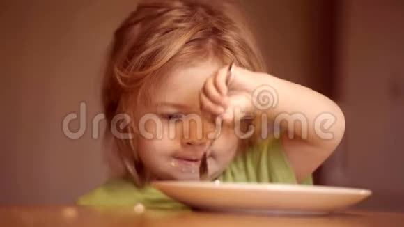 年轻的孩子坐在桌子上吃健康的食物脸上有滑稽的表情孩子吃东西可爱的孩子在吃东西视频的预览图