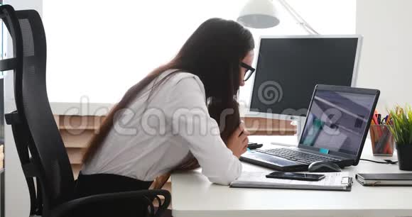 女商人放下杯子把头放在笔记本电脑上视频的预览图