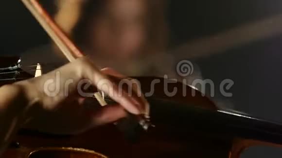 女人在小提琴的弦上鞠躬黑烟背景关门视频的预览图