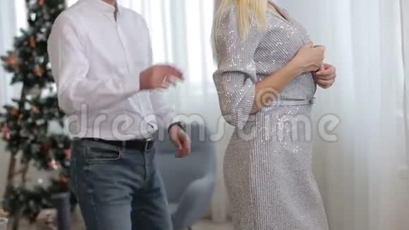 年轻快乐的金发女人拥抱她的丈夫在圣诞节装饰的房间在里面肖像视频的预览图