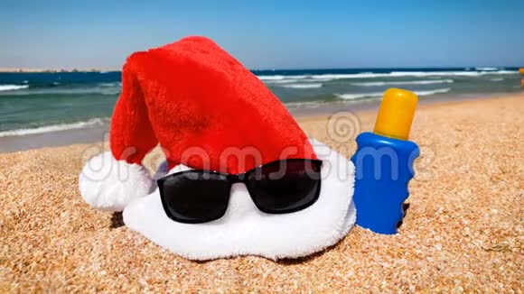 圣诞老人帽子躺在沙滩上的4K镜头在热带岛屿庆祝圣诞节的概念视频的预览图