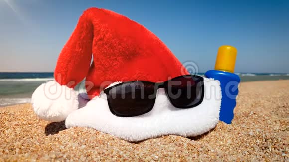 4k视频中的圣诞帽太阳镜和防晒霜躺在沙滩上过冬的概念视频的预览图