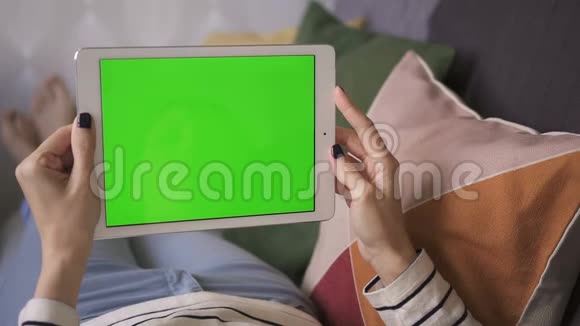 美国商界女性躺在家里的沙发上手里拿着一款绿色屏幕平板电脑视频的预览图