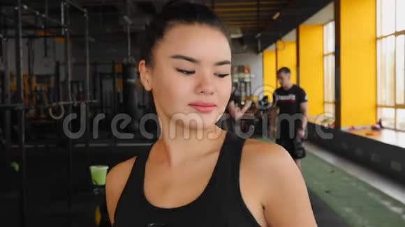 漂亮的亚洲女孩在健身房看着相机和微笑后训练视频的预览图