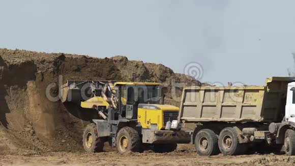 推土机在施工现场装载运砂车建筑设备履带式推土机移动沙子视频的预览图