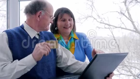 在线支付快乐的老年人用电子货币和笔记本电脑购买互联网视频的预览图