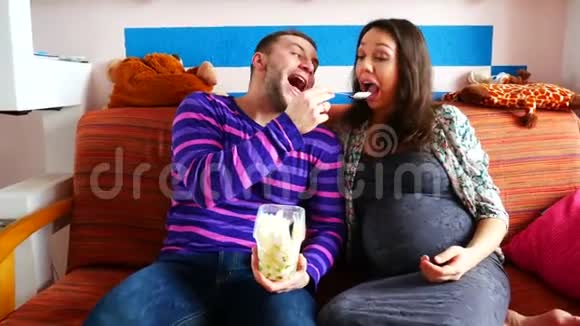 一对年轻夫妇用冰淇淋互相喂饭坐在沙发上视频的预览图