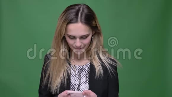 年轻有魅力的潮人白种人女性的特写镜头使用绿色背景的手机视频的预览图