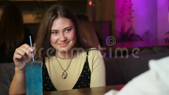年轻女子坐在咖啡馆里和一个微笑的男人交谈开心的约会喝着鸡尾酒视频的预览图