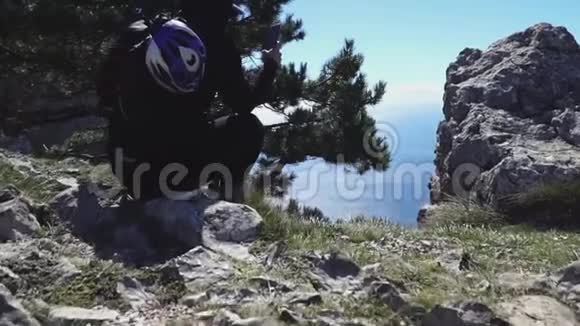 一个背着背包的人坐在海边的岩石上视频的预览图